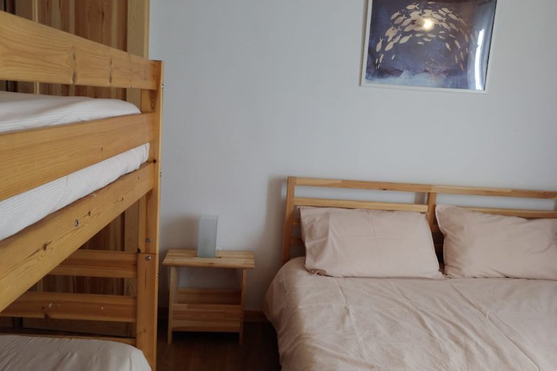 Una accogliente camera da letto che affaccia sul giardino, con soffitto e arredamento in legno più un letto a castello.