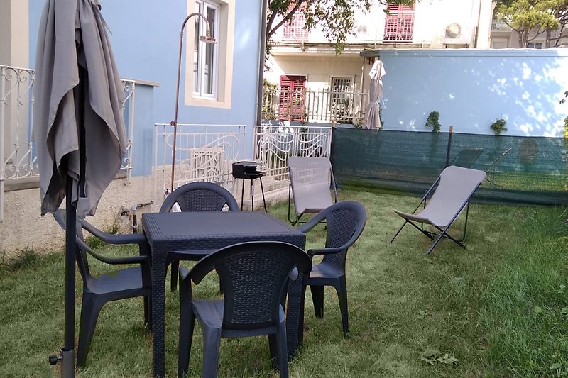 Ampio giardino attorno alla villetta liberty con sdraio, ombrellone, tavoli, sedie , barbecue e doccia esterna in rame.