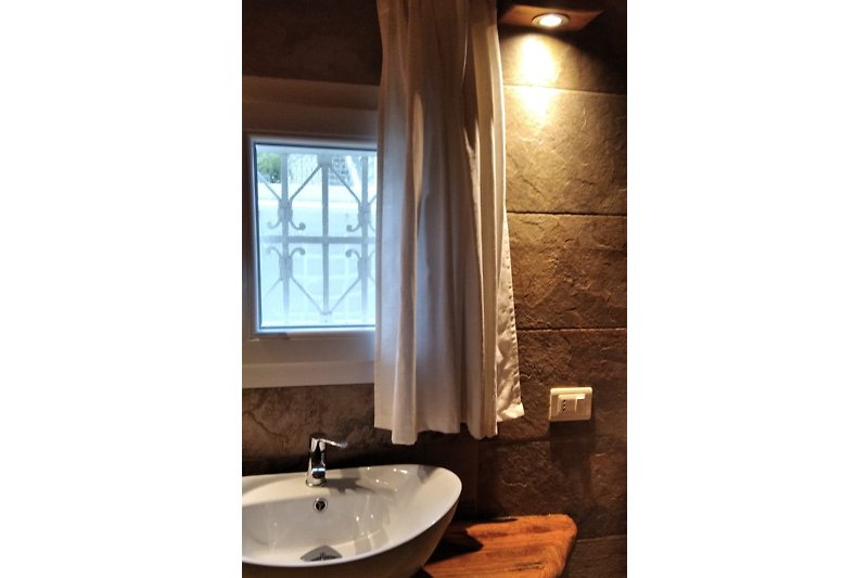 Un bellissimo bagno moderno tipo pietra e soffitto in legno con arredamenti in legno.