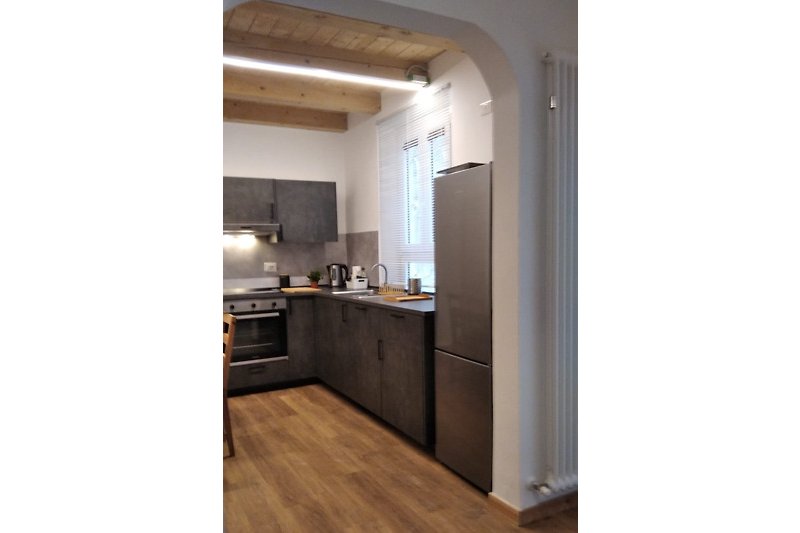 Una bella e accogliente cucina moderna con soffitto e mobili in legno, piano di lavoro e elettrodomestici.