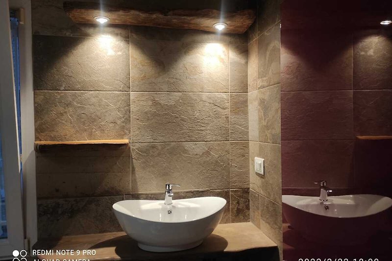 Un bellissimo bagno moderno tipo pietra con soffitto in legno e con arredamenti in legno.