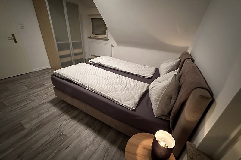 Stilvolles Schlafzimmer mit Holzboden und gemütlichem Bett.