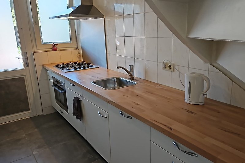 Moderne keuken met houten kasten, aanrecht en gasfornuis.