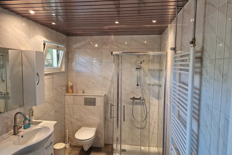 Moderne badkamer met spiegel, wastafel en douche.