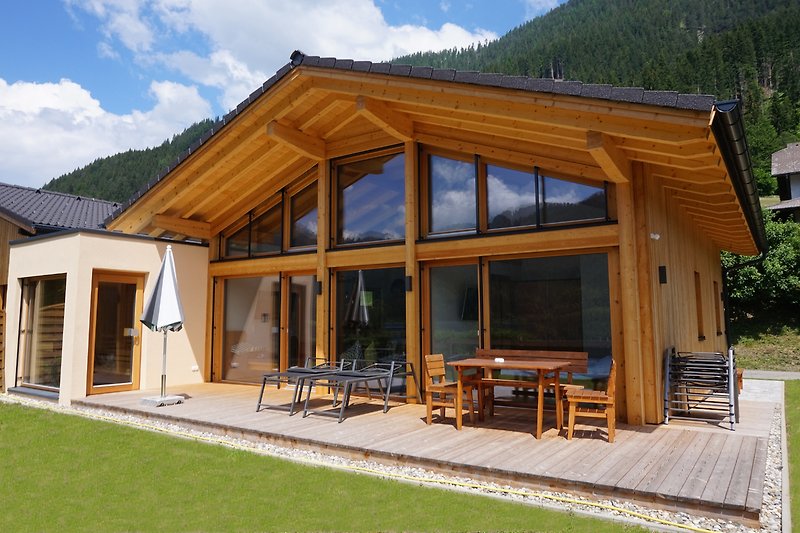 Holzhaus mit Terrasse und Gartenmöbeln in den Bergen.