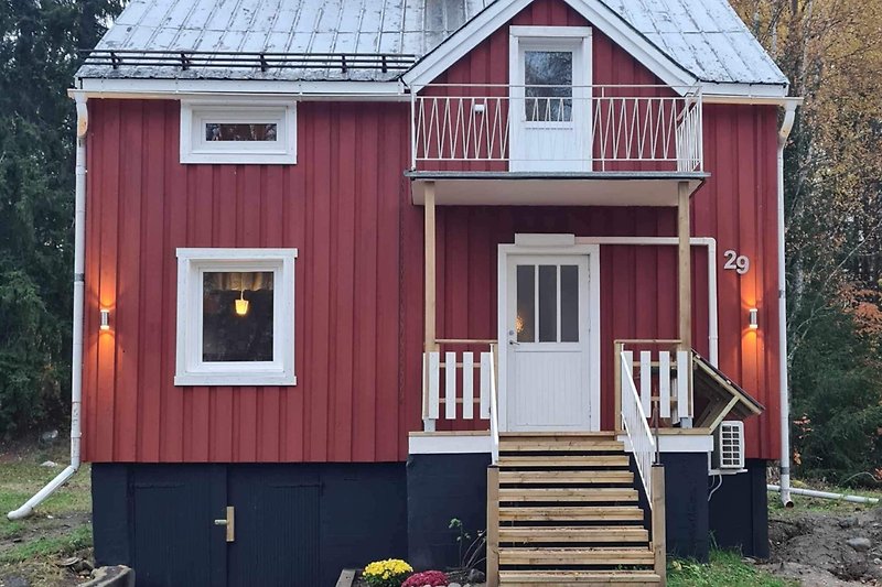 Ein charmantes Haus mit einem roten Dach und einem blühenden Garten.