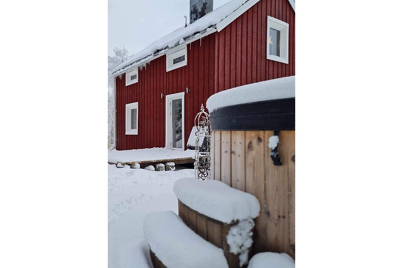 Ein winterliches Holzhaus mit verschneitem Dach und gemütlicher Einrichtung.