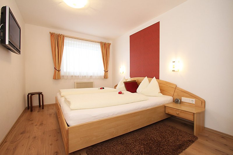 Harmonisiertes Schlafzimmer mit Holzboden und Fußläufer im Apartment Steiner Leogang