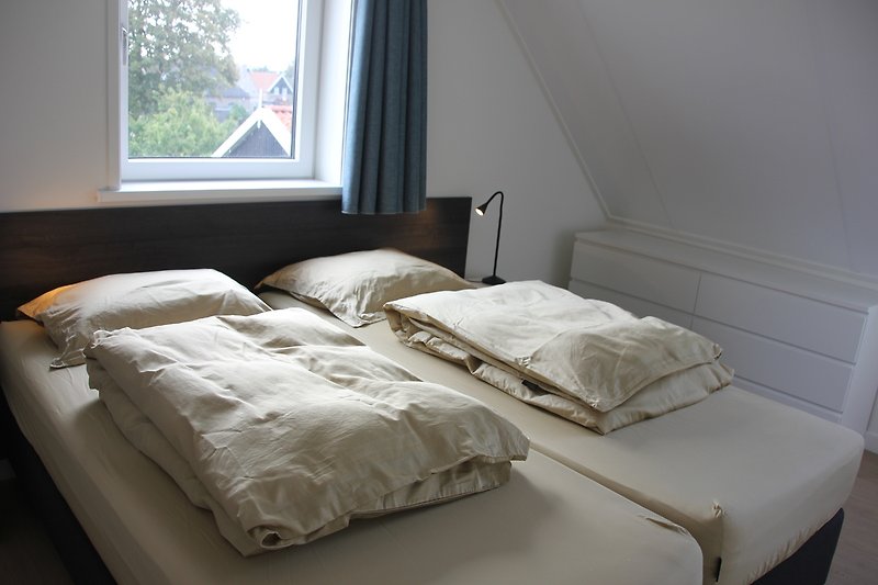 Gemütliches Schlafzimmer mit stilvollem Holzbett und Fensterdekoration.