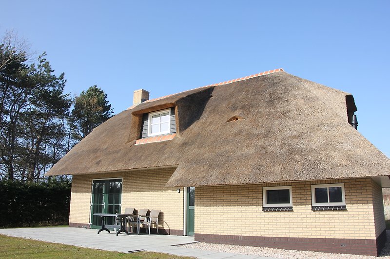 Gemütliches Ferienhaus mit thatched Dach, Holzverkleidung und grüner Landschaft.