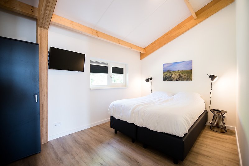 Stilvolles Schlafzimmer mit bequemem Bett und hochwertigem Holzboden.
