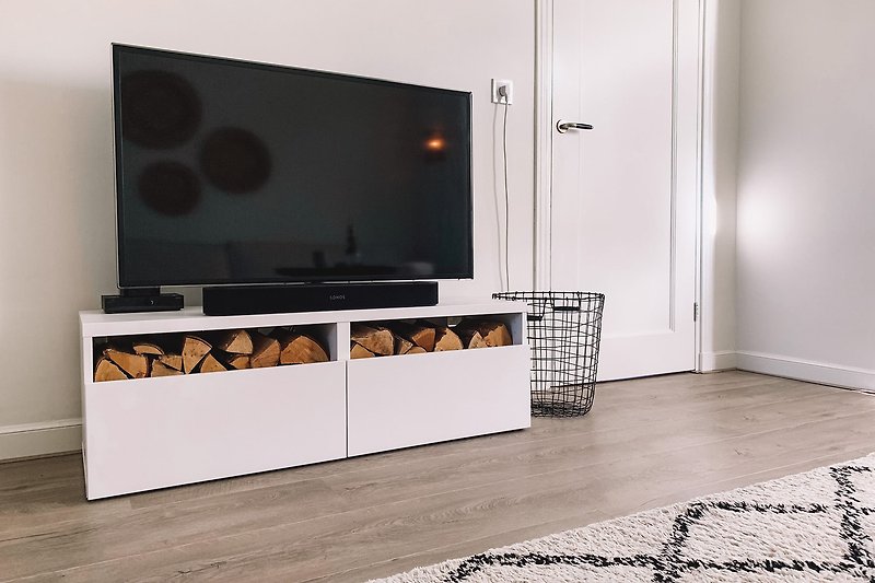 Hippe woonkamer met houten vloer en een grote televisie.