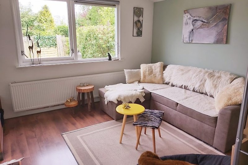 Een comfortabele woonkamer met houten meubels en een groot raam.