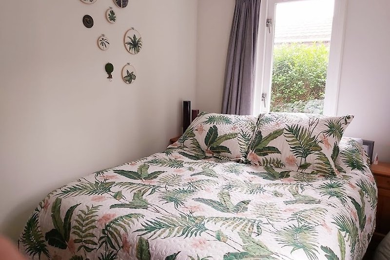 Een comfortabele slaapkamer met een houten bedframe en zacht beddengoed.