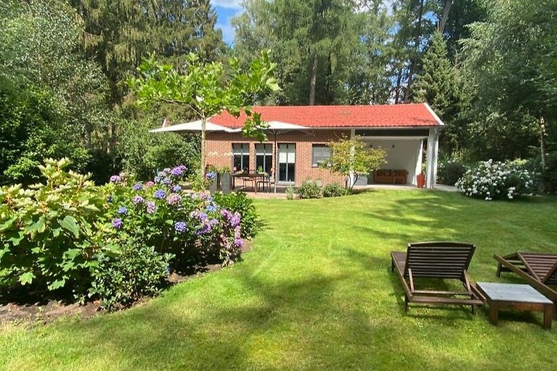 Ein charmantes Landhaus mit einem blühenden Garten und einem malerischen Hintergrund.