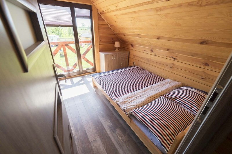 Gemütliches Schlafzimmer mit Holzbett und schöner Aussicht auf den Baum.