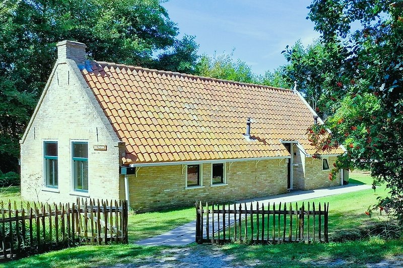 Rotes Backsteinhaus mit Garten und Schornstein im Dorf.