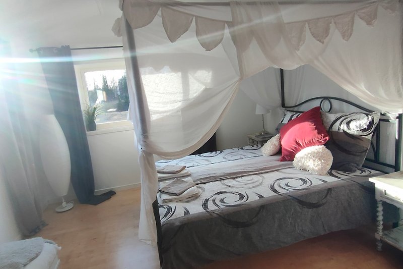 Gemütliches Schlafzimmer mit stilvollem Himmelbett, Holzboden und gemütlicher Einrichtung.