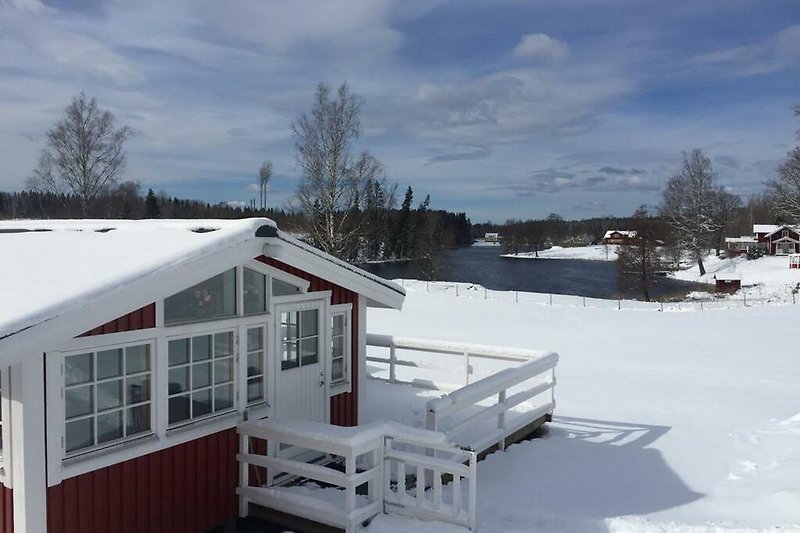 Schönes Winterhaus mit verschneitem Dach, Holzverkleidung und gemütlichem Fenster.