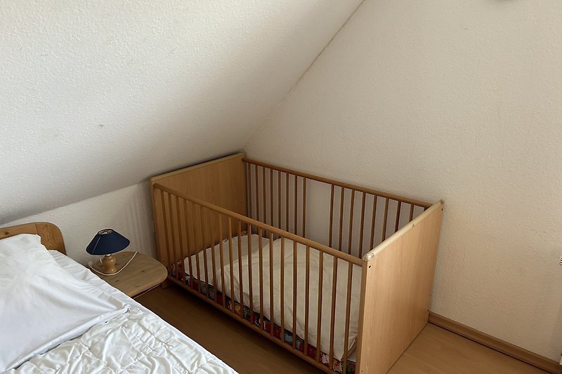 Gemütliches Schlafzimmer mit Babybett neben Doppelbett