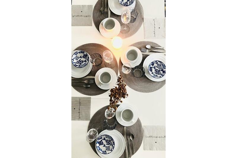Ein stilvolles Tischarrangement mit Porzellan, Besteck und Tischdecke.