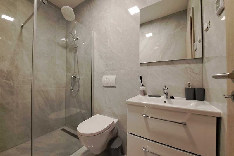 Badezimmer mit lila Wand, Spiegel, Waschbecken und Dusche.