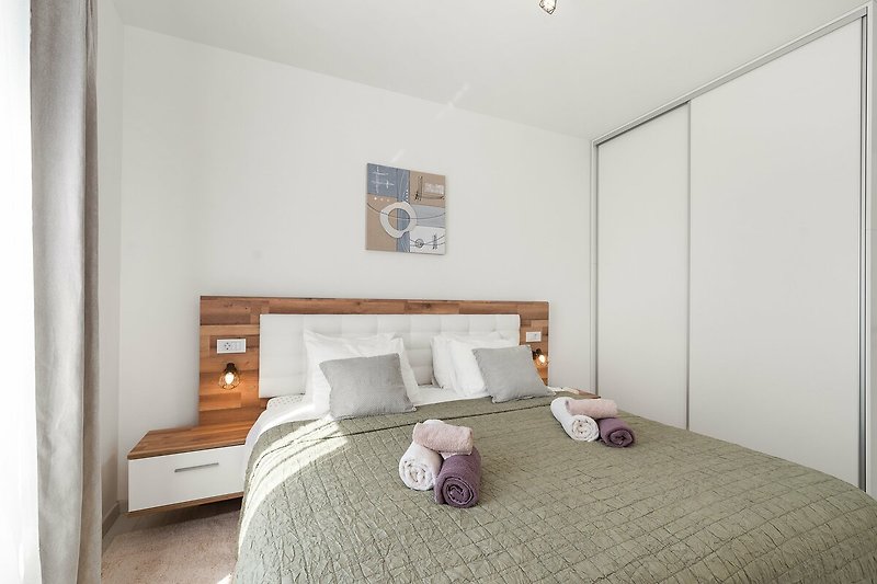 A comfortable bedroom with stylish wood flooring and elegant bedding.