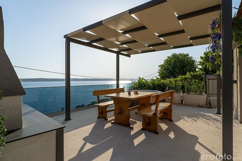 A beautiful waterfront property with a wooden deck and outdoor furniture.