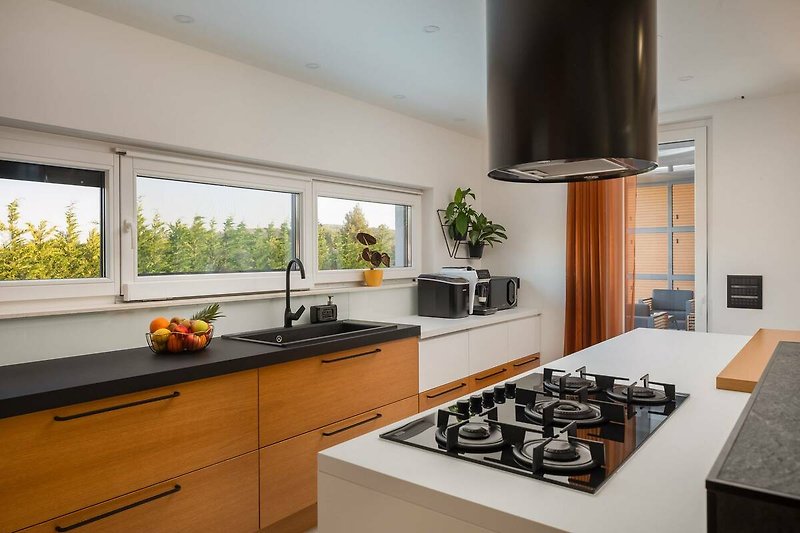 A modern kitchen with wood cabinetry, granite countertop, and a gas stove.
