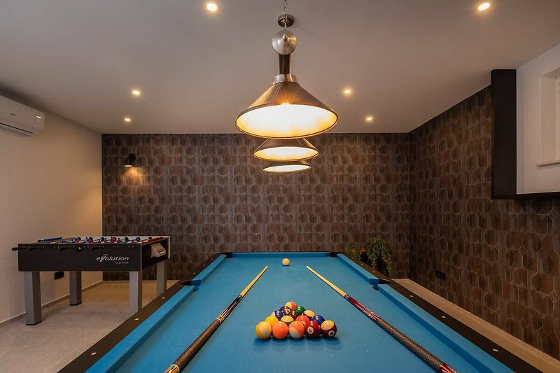 A stylish billiard room with a table, baize, and sports equipment.