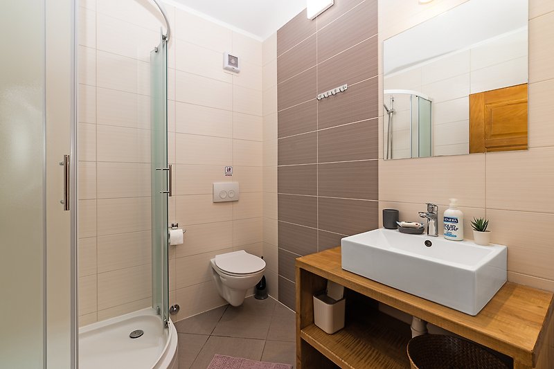 A modern bathroom with a purple sink, glass shower, and sleek fixtures.