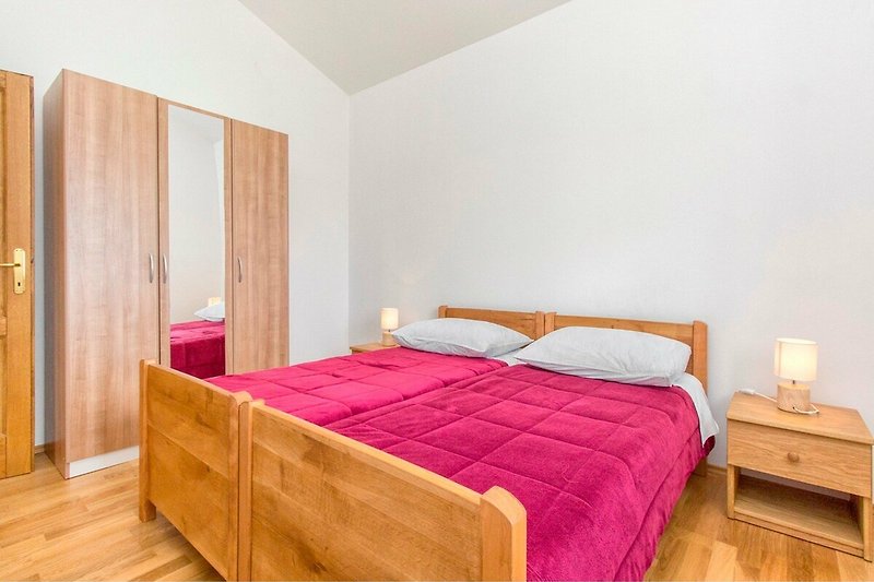 Gemütliches Schlafzimmer mit Holzmöbeln und gemusterten Bettwäsche.