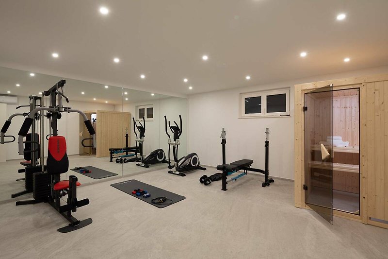 A well-equipped gym with exercise machines and hardwood flooring.