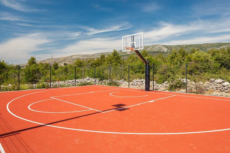 A vibrant basketball court with players enjoying a game under the clear sky.