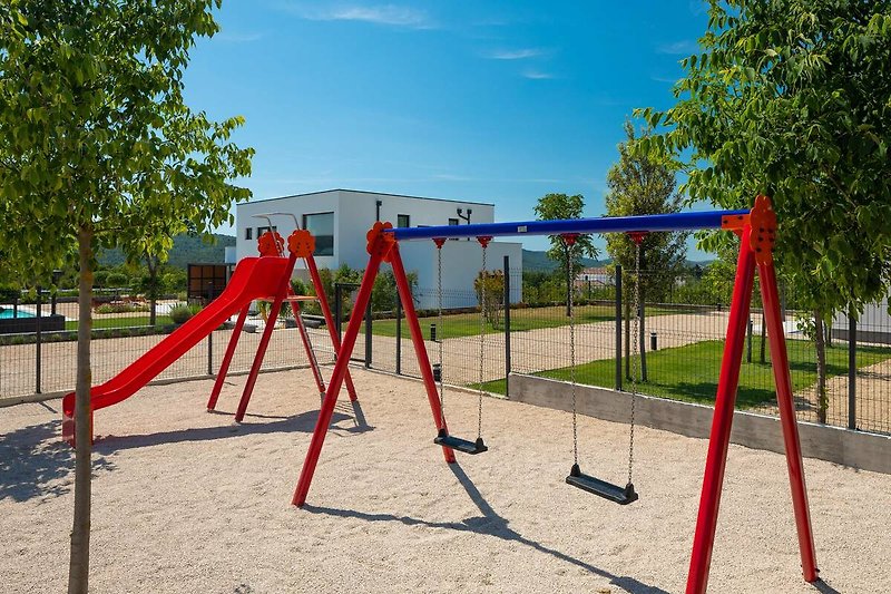 A fun playground with swings, slides, and a lush green park.