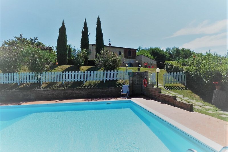 Schönes Haus mit Pool, grünem Garten und blauem Himmel, umgeben von Natur und einem Swimmingpool.
