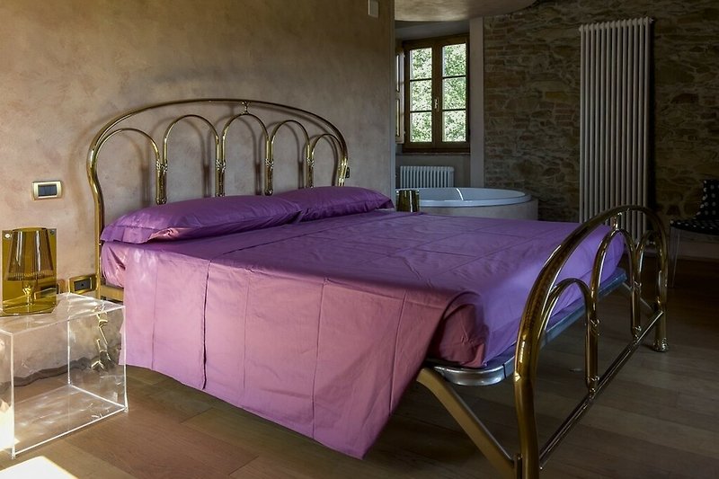 Gemütliches Schlafzimmer mit magenta Bettwäsche und Holzbett.