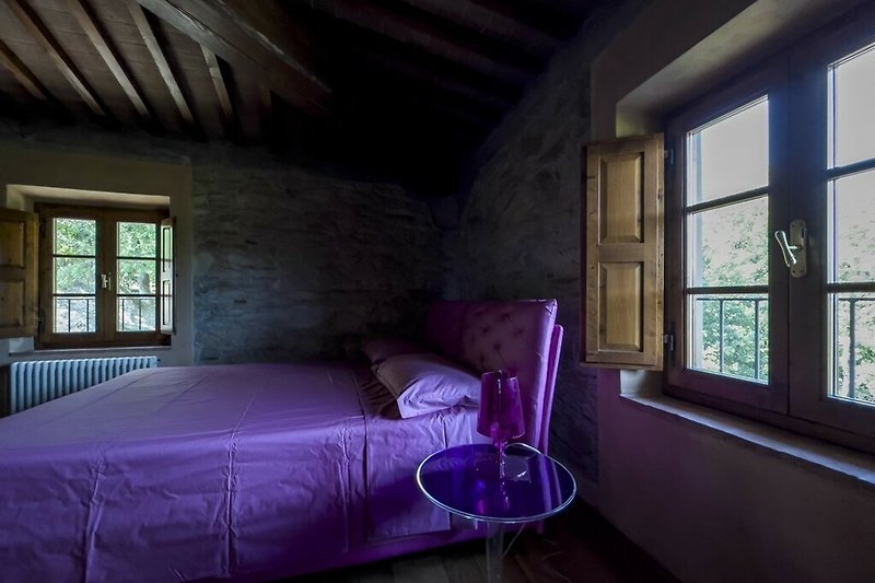 Gemütliches Schlafzimmer mit lila Bettwäsche und Holzbett.