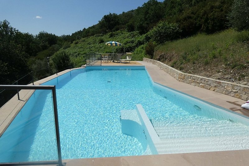Schönes Ferienhaus mit Pool, umgeben von Natur und Outdoor-Möbeln.