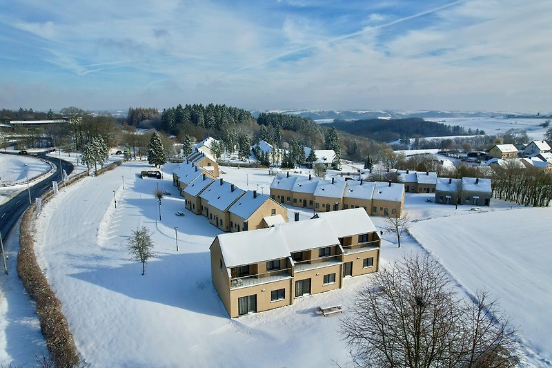 Winterliche Stadtansicht mit Bergen und verschneiten Häusern.