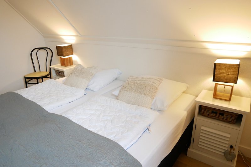 Gezellige slaapkamer met sfeervolle verlichting en comfortabel beddengoed.