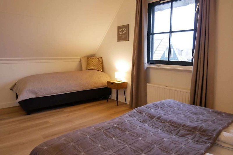 Comfortabele slaapkamer met houten meubels en zachte beddengoed.
