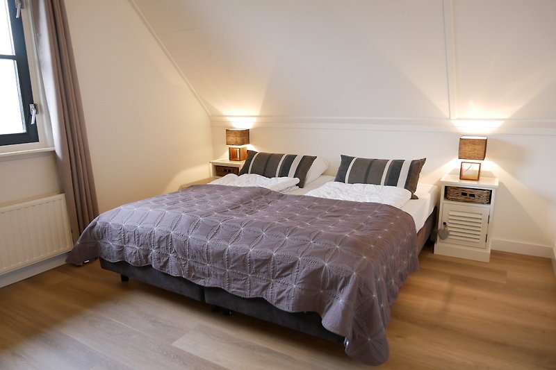 Gezellige slaapkamer met houten meubels en comfortabel beddengoed.