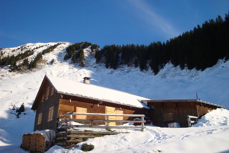 Bergiges Haus mit schneebedecktem Dach und malerischer Landschaft.