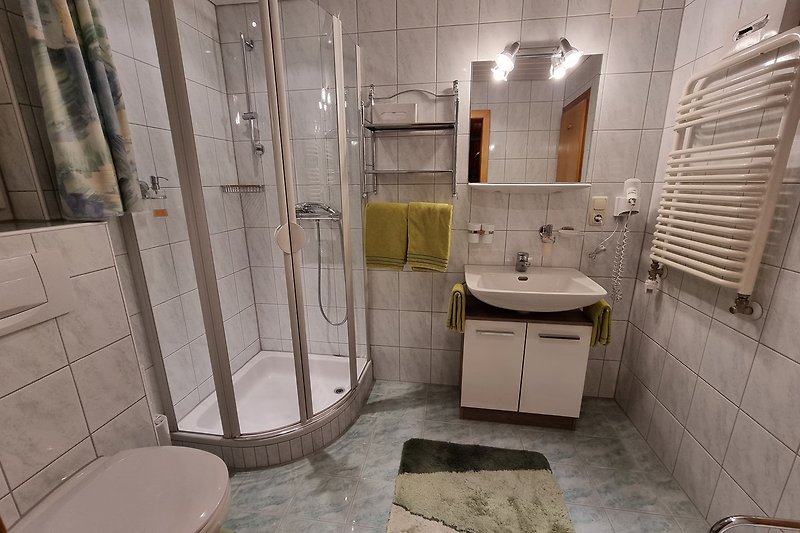 Eltern-Badezimmer mit Spiegel, Waschbecken, Toilette und Dusche.