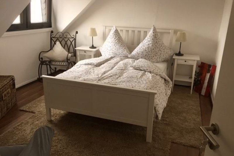 Gemütliches Schlafzimmer mit französischem Doppelbett, ruhig zum Grundstück gelegen, mit Sessel.