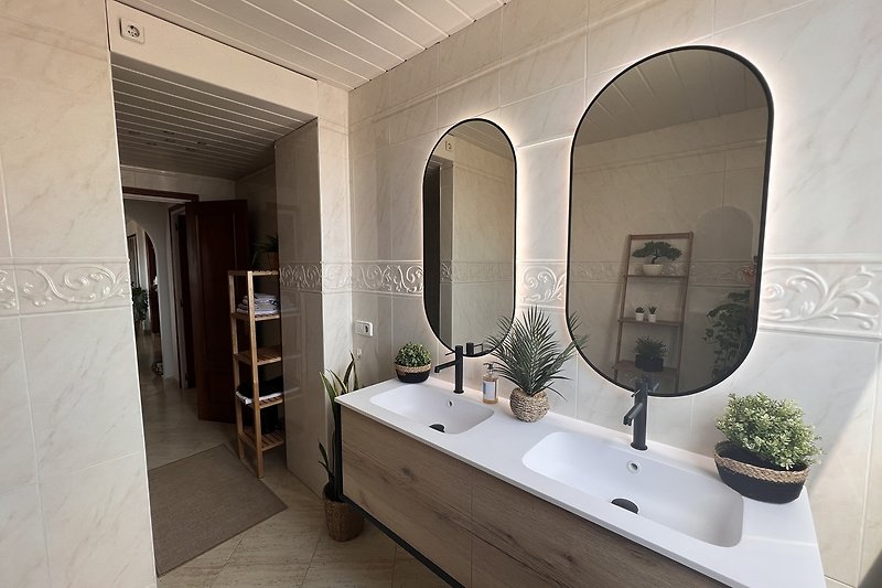 Hermoso baño con espejo, planta y grifo.