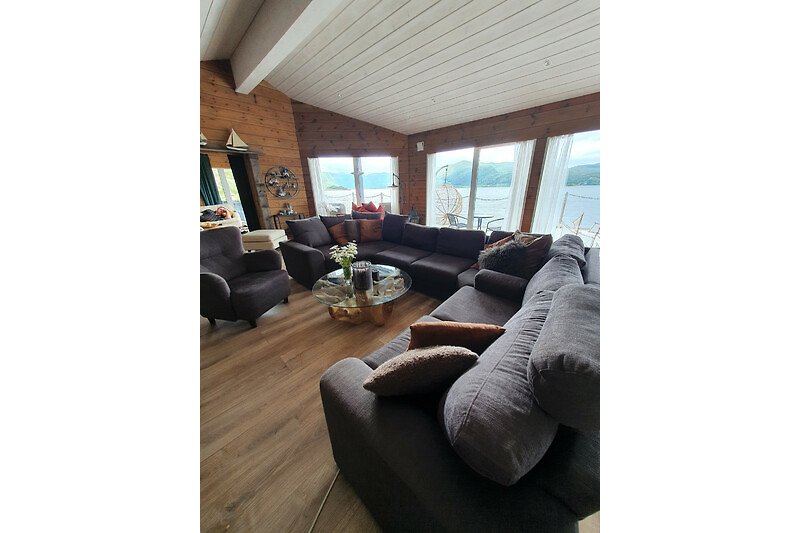 A comfortable brown couch in a well-designed living room with wood furniture and natural light.