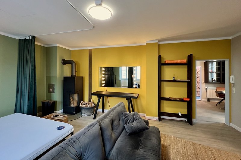 Stilvolles Wohnzimmer mit bequemer Couch, grossem Bett (180x200) und moderner Einrichtung.