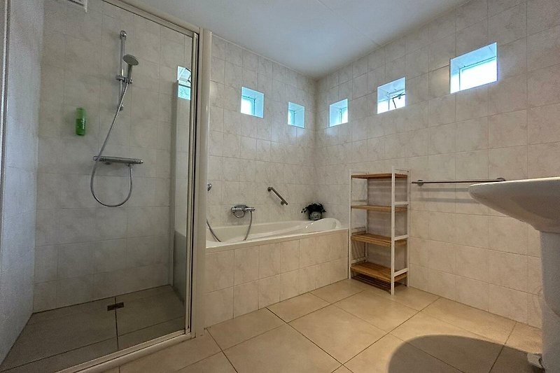 Een moderne badkamer op de begane grond met een stijlvolle douche en glazen douchewand.